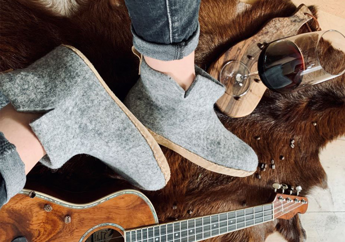 Jemand tr�gt Huettenschuhe, die sich neben einem Glas Wein und einer Gitarre befinden
