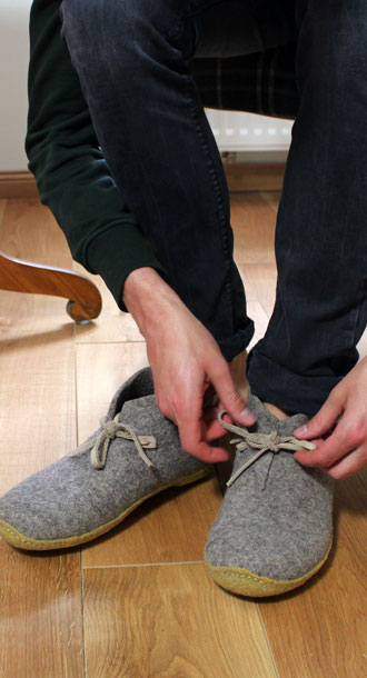 Eine Person schn�rt den WoolFit Slipper zu.
